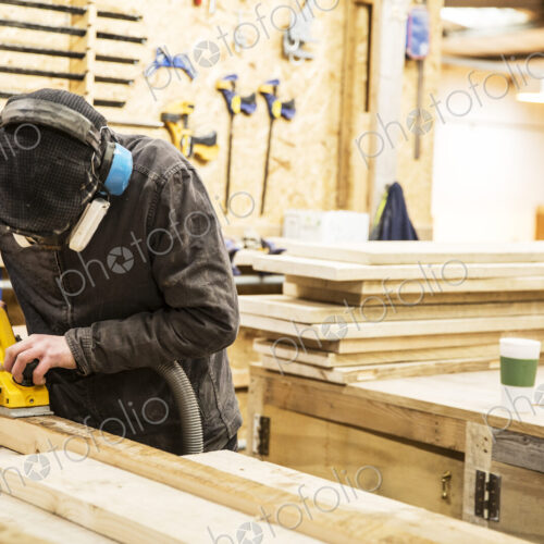 Man wearing ear protectors, protective goggles and dust mask standing in a warehouse,… Man wearing ear protectors, protective goggles and dust mask standing in a warehouse,…