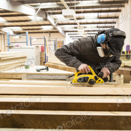 Man wearing ear protectors, protective goggles and dust mask standing in a warehouse,… Man wearing ear protectors, protective goggles and dust mask standing in a warehouse,…