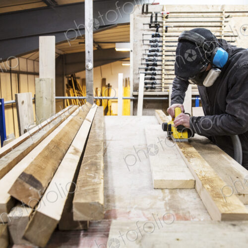 Man wearing ear protectors, protective goggles and dust mask standing in a warehouse,… Man wearing ear protectors, protective goggles and dust mask standing in a warehouse,…