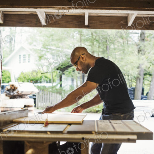 Man wearing glasses working in a lumber yard.