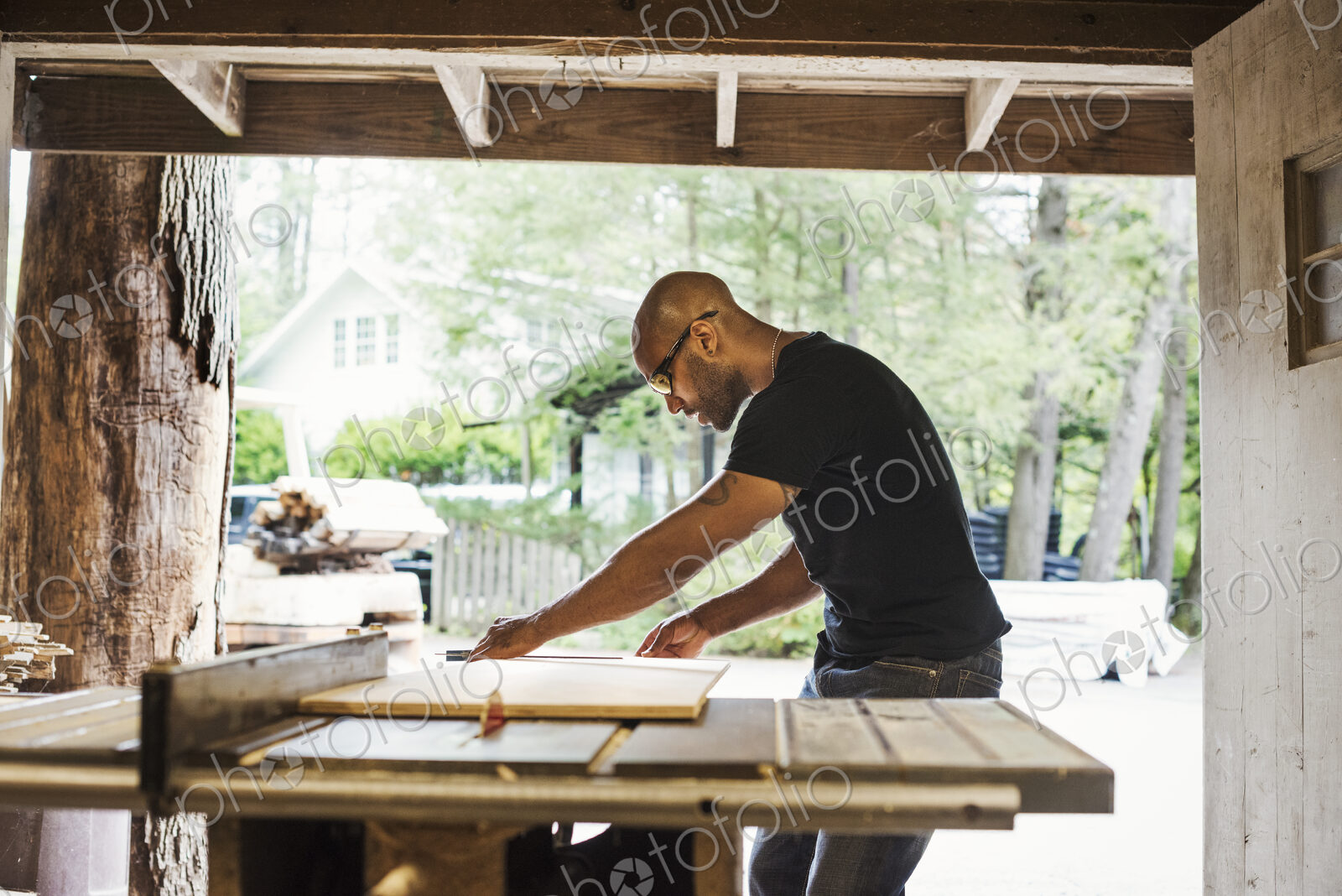 Man wearing glasses working in a lumber yard.