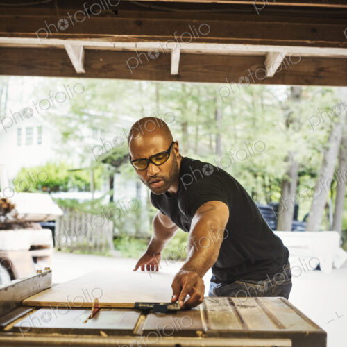 Man wearing glasses working in a lumber yard.