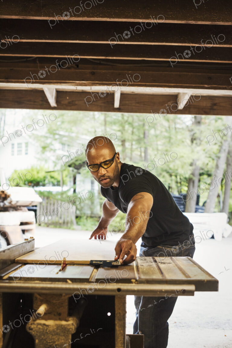 Man wearing glasses working in a lumber yard.