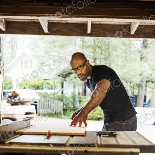 Man wearing glasses working in a lumber yard.