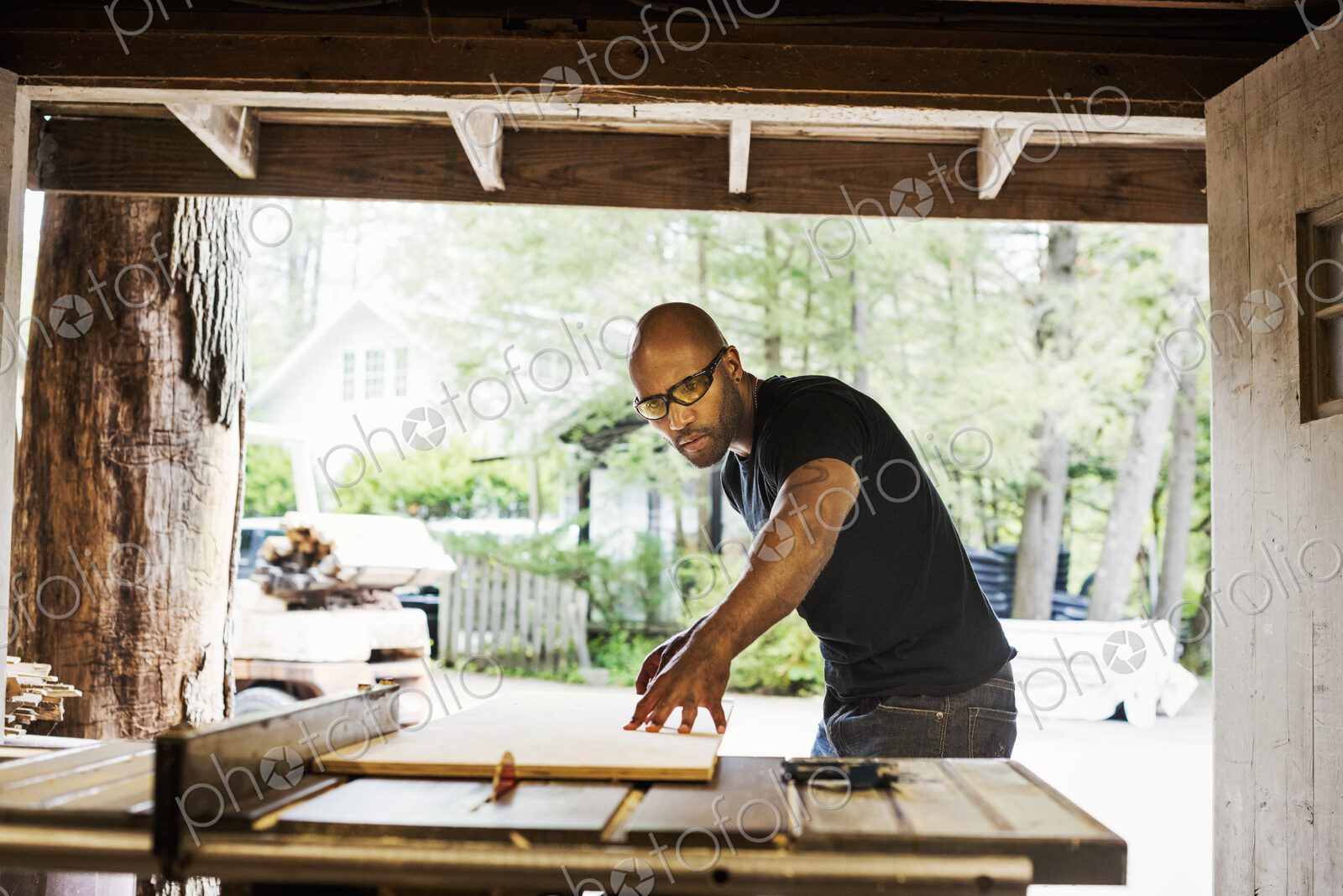 Man wearing glasses working in a lumber yard.