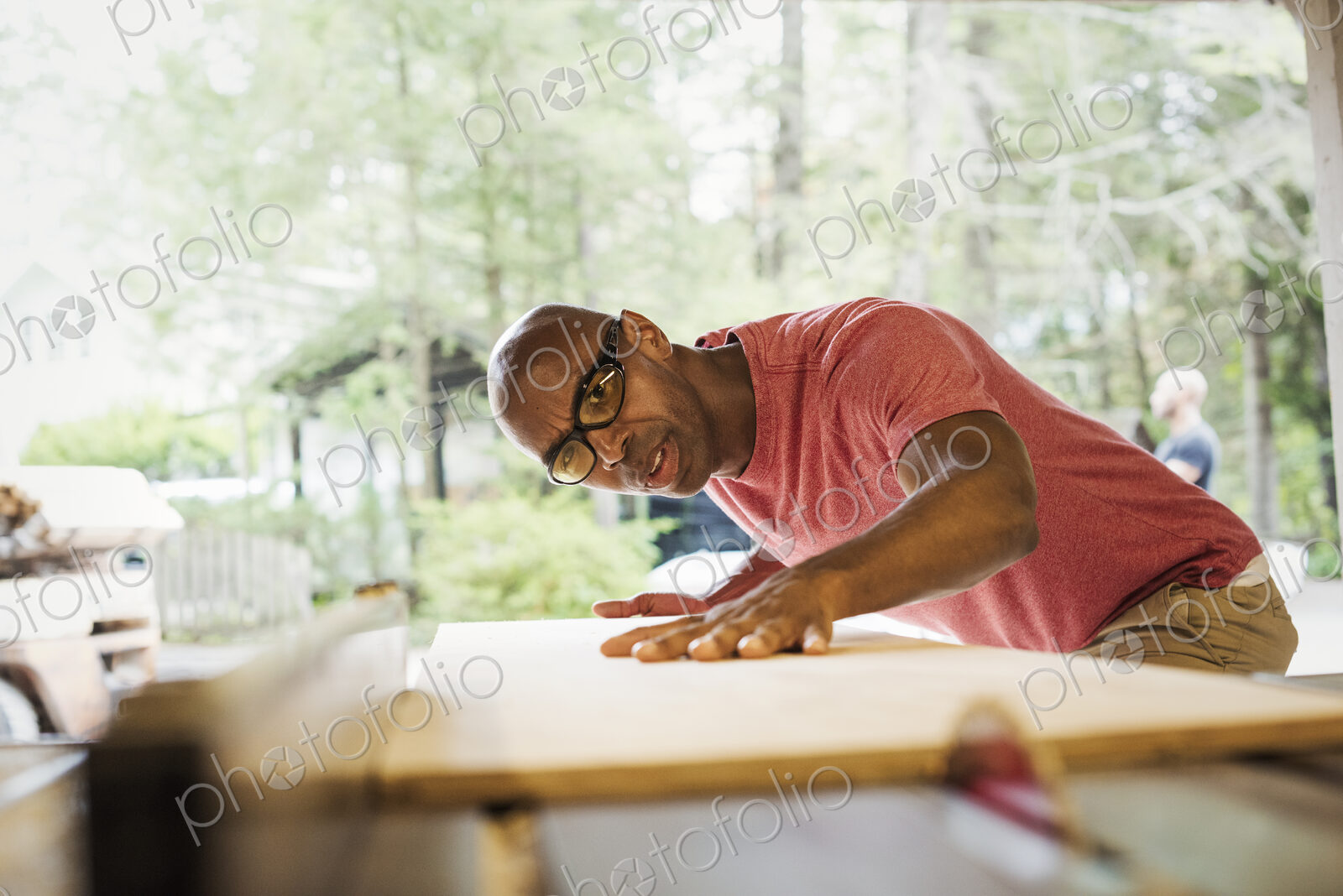 Man wearing glasses working in a lumber yard.