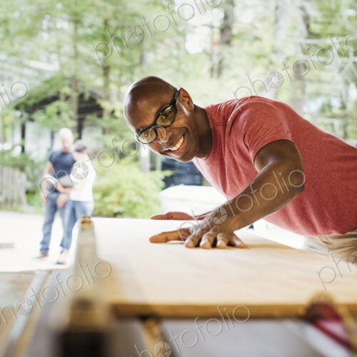 Man wearing glasses working in a lumber yard.