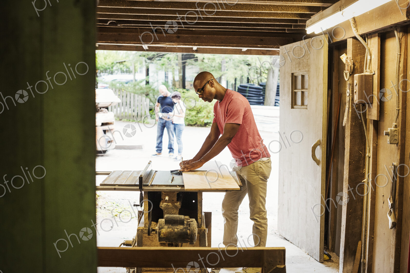 Man wearing glasses working in a lumber yard.