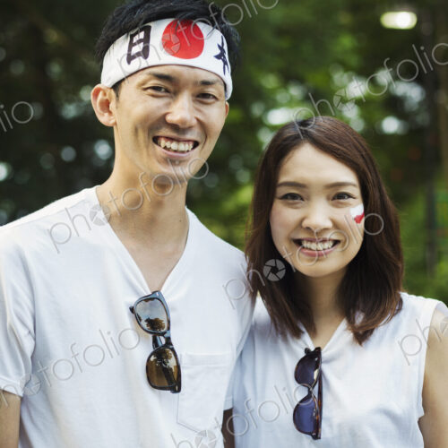Man wearing headband and young woman with Japanese flag painted on her cheek,