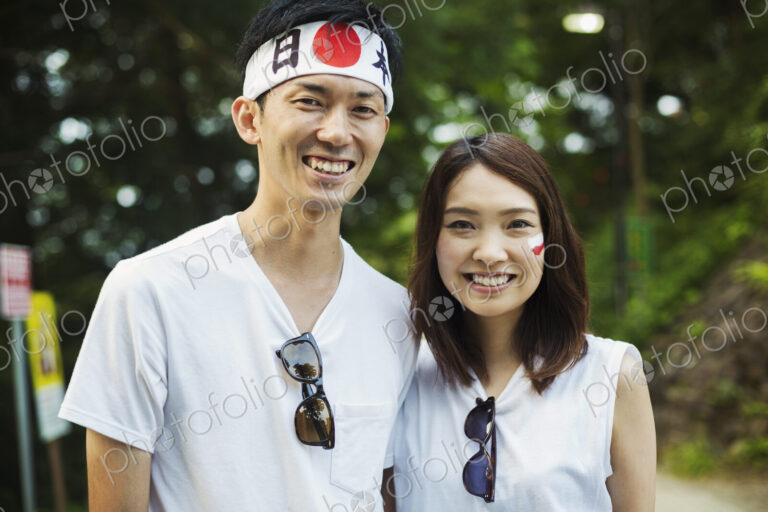 Man wearing headband and young woman with Japanese flag painted on her cheek,