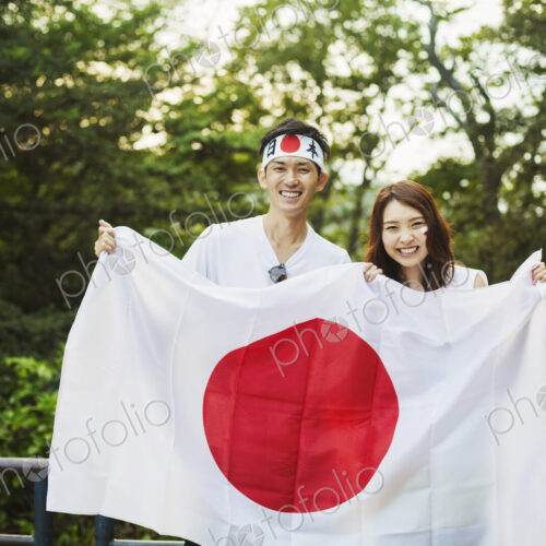 Man wearing headband and young woman with face paint holding a Japanese flag
