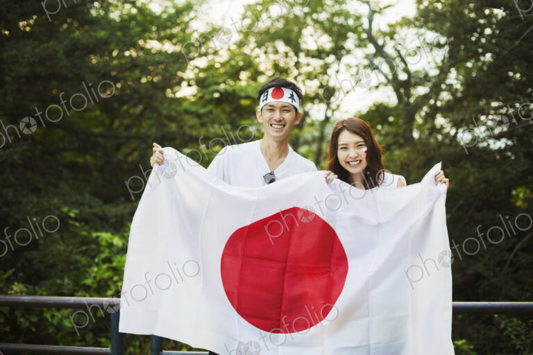 Man wearing headband and young woman with face paint holding a Japanese flag