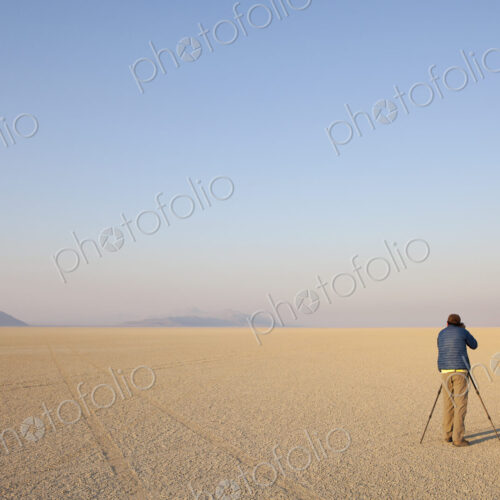 Man with camera and tripod on the flat saltpan or playa of Black Rock desert, Nevada.