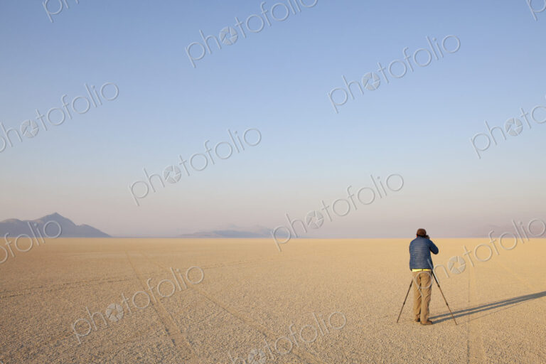 Man with camera and tripod on the flat saltpan or playa of Black Rock desert, Nevada.