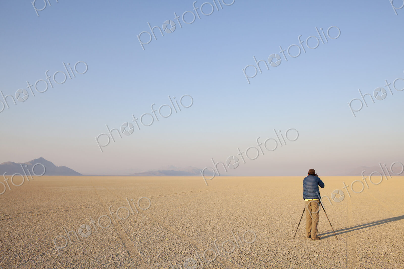 Man with camera and tripod on the flat saltpan or playa of Black Rock desert, Nevada.