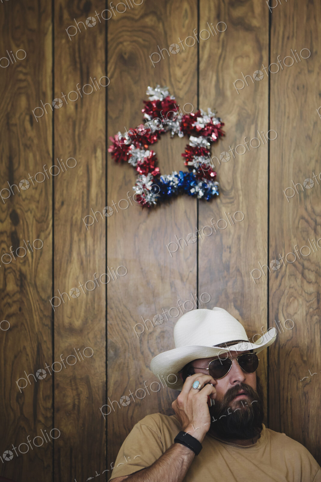 Man with long beard and cowboy hat talking on cell phone.