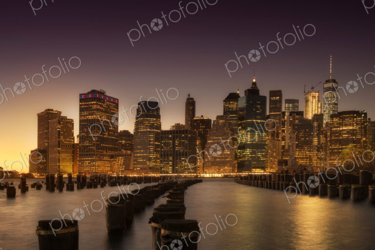 Manhattan skyscrapers lit up at dawn.