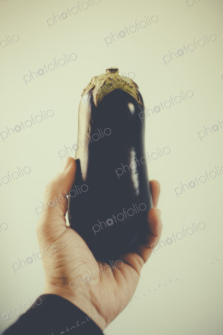 Man's hand holding organic eggplant.