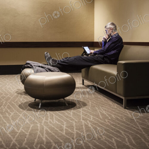 Mature businessman with his feet up, resting in an armchair, looking at his mobile phone. Mature businessman with his feet up, resting in an armchair, looking at his mobile phone.