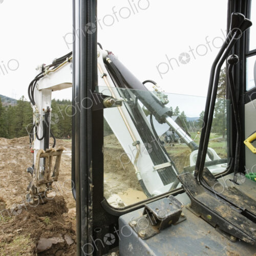 Mechanical digger excavating ground in rural environment.