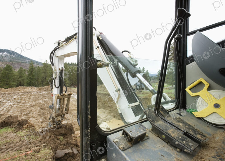 Mechanical digger excavating ground in rural environment.