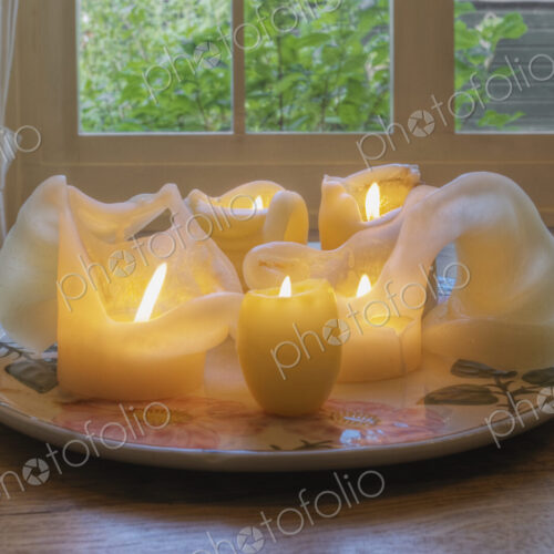 Melted wax candles on plate on dining table. Melted wax candles on plate on dining table.