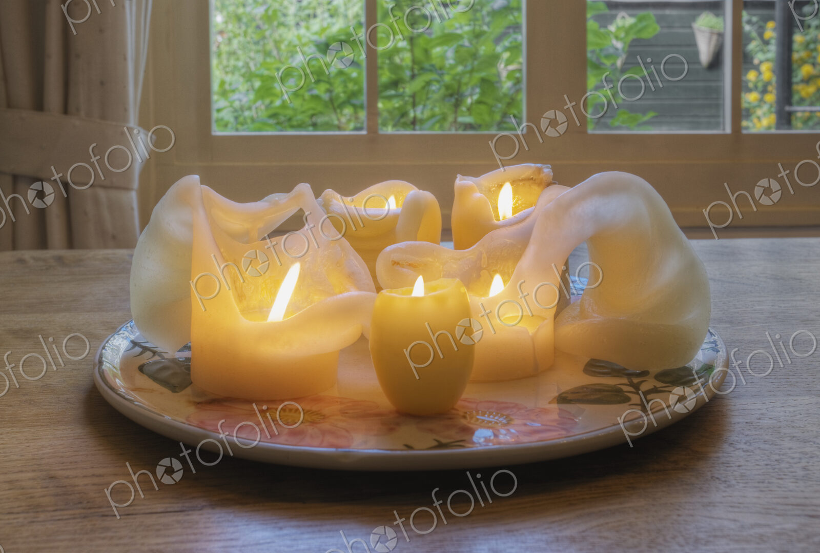 Melted wax candles on plate on dining table.