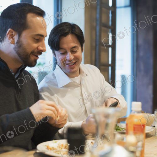 Men sharing text at restaurant table