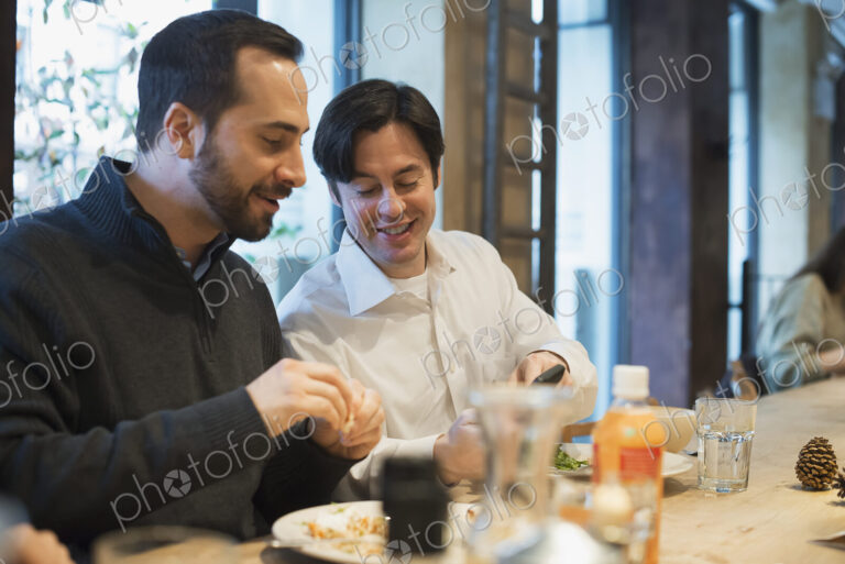 Men sharing text at restaurant table