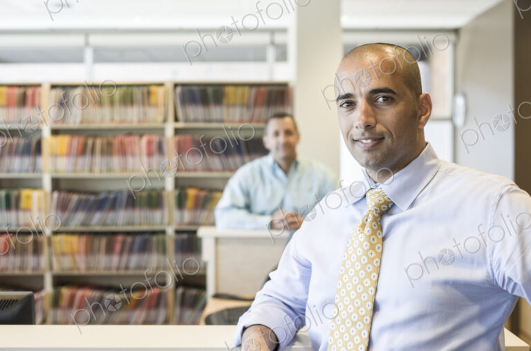 Middle eastern male dentist in his office with patient file folders in the background.