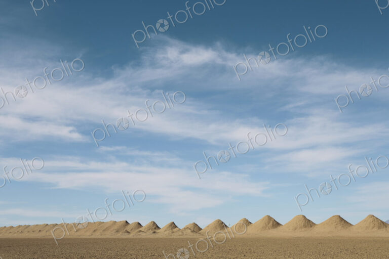 Mining tailings creating row of dirt piles in desert.