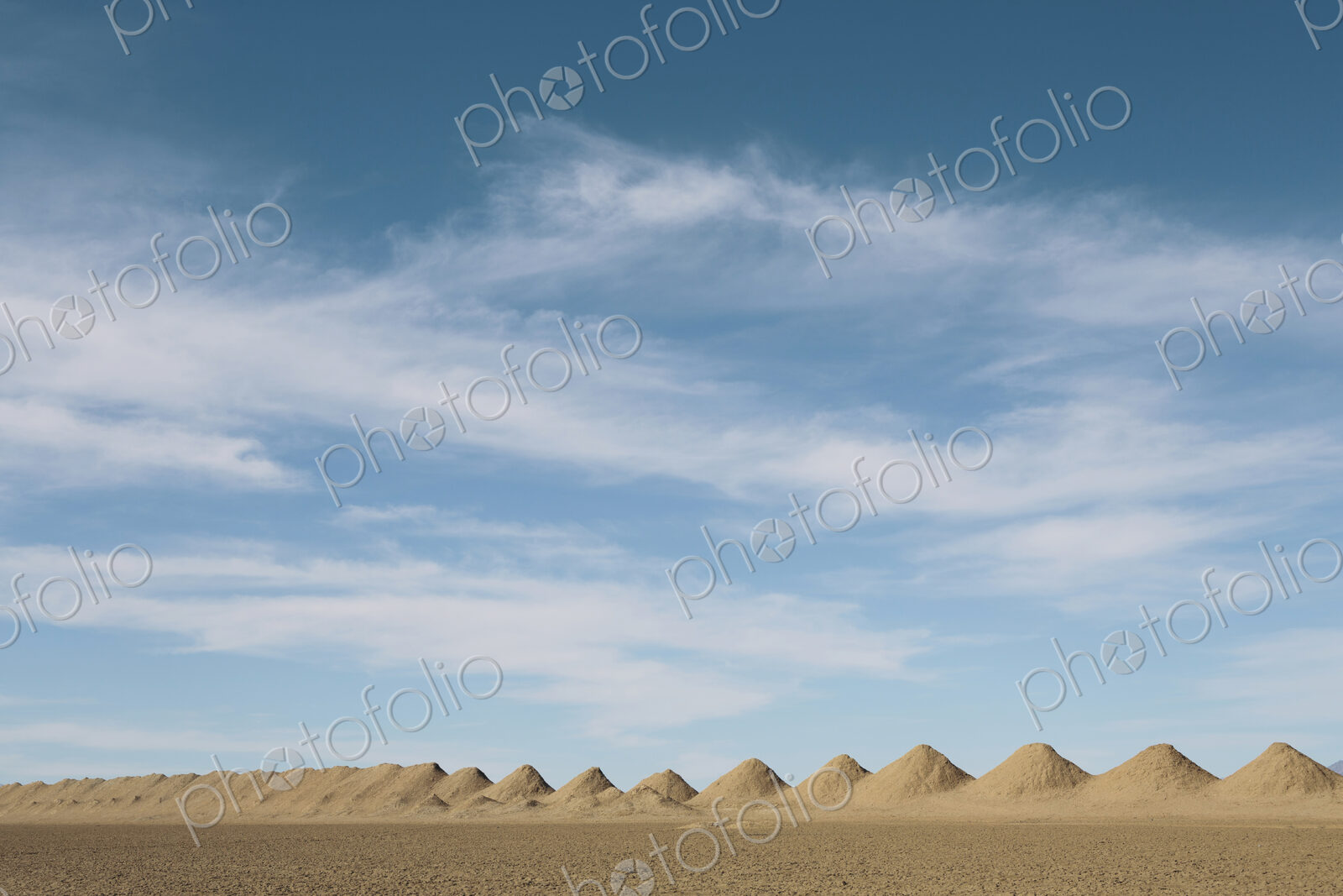 Mining tailings creating row of dirt piles in desert.