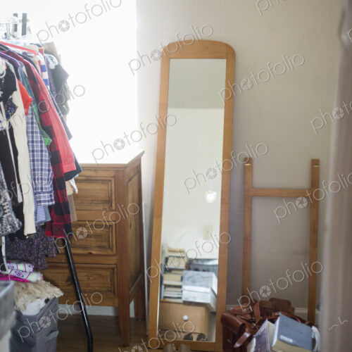 Mirror, chest of drawers, clothes rack and shoes in a bedroom.