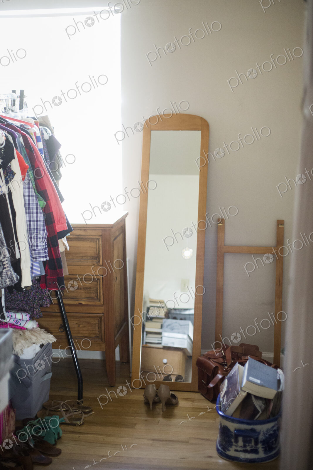 Mirror, chest of drawers, clothes rack and shoes in a bedroom.