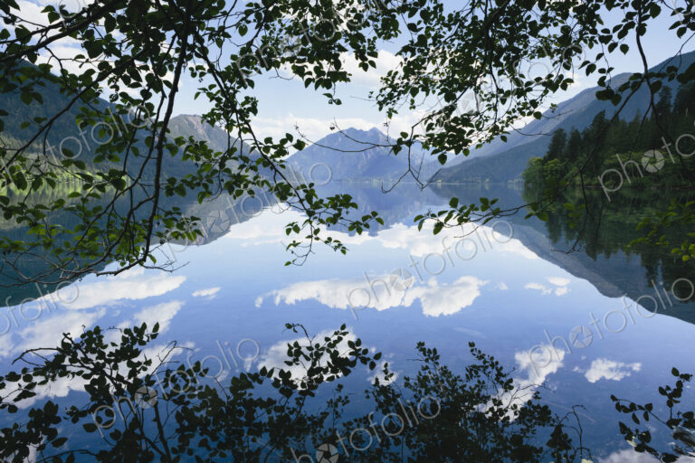 Mirror reflections, the sky and clouds reflected in the surface of hte water of Lake…