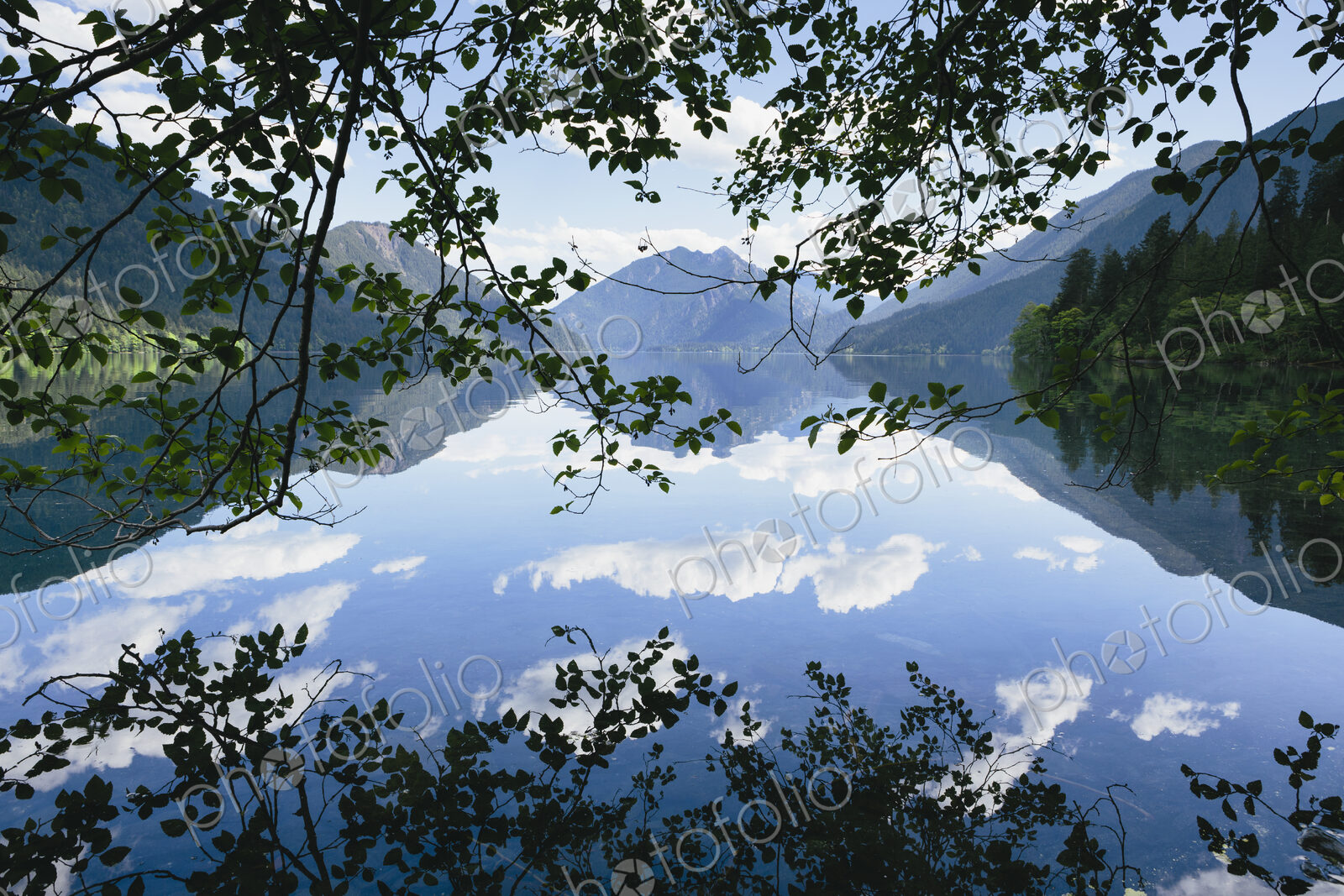 Mirror reflections, the sky and clouds reflected in the surface of hte water of Lake…