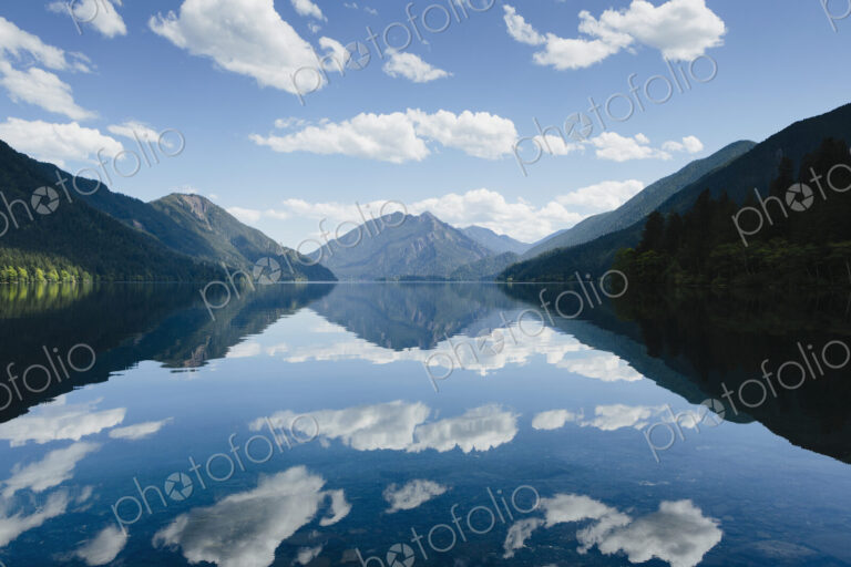 Mirror reflections, the sky and clouds reflected in the surface of hte water of Lake…