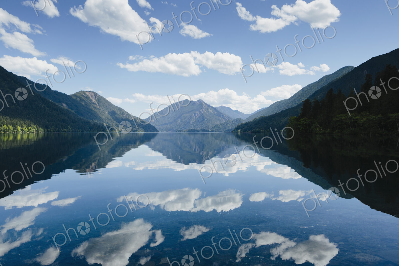 Mirror reflections, the sky and clouds reflected in the surface of hte water of Lake…