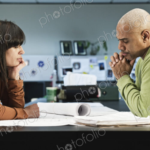 Mixed Race woman and Black man going over a project in their business office.