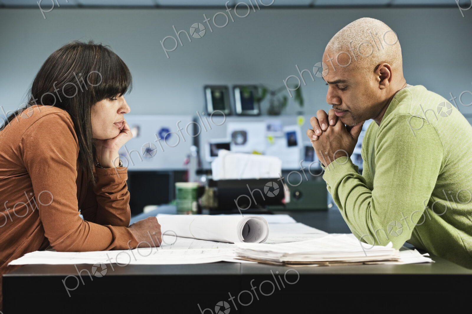 Mixed Race woman and Black man going over a project in their business office.