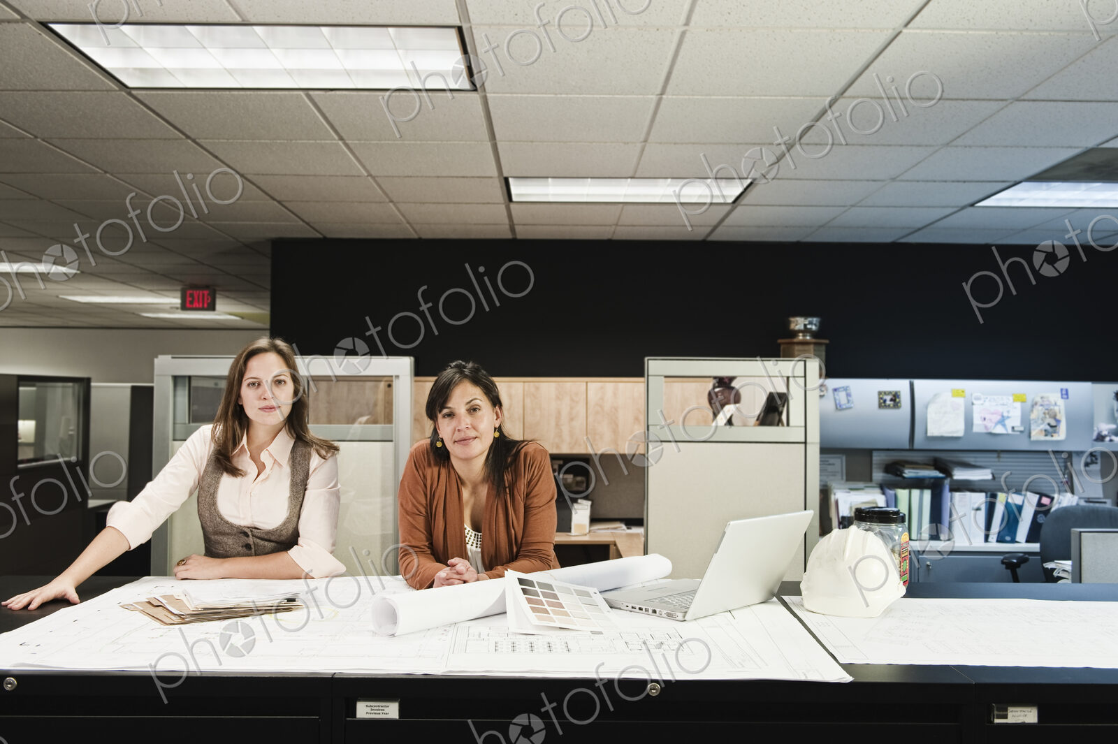 Mixed race and Caucasian females working on a project at a table in their office.