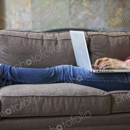 Mixed race caucasian woman at home on the couch working on a lap top computer with her… Mixed race caucasian woman at home on the couch working on a lap top computer with her…