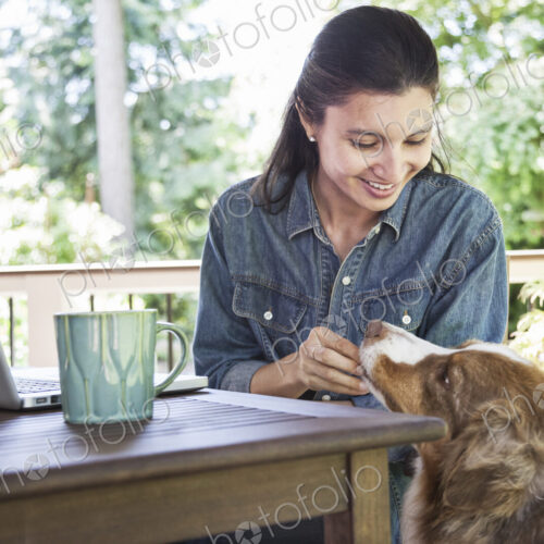 Mixed race caucasian woman working on her laptop at home with her dog. Mixed race caucasian woman working on her laptop at home with her dog.