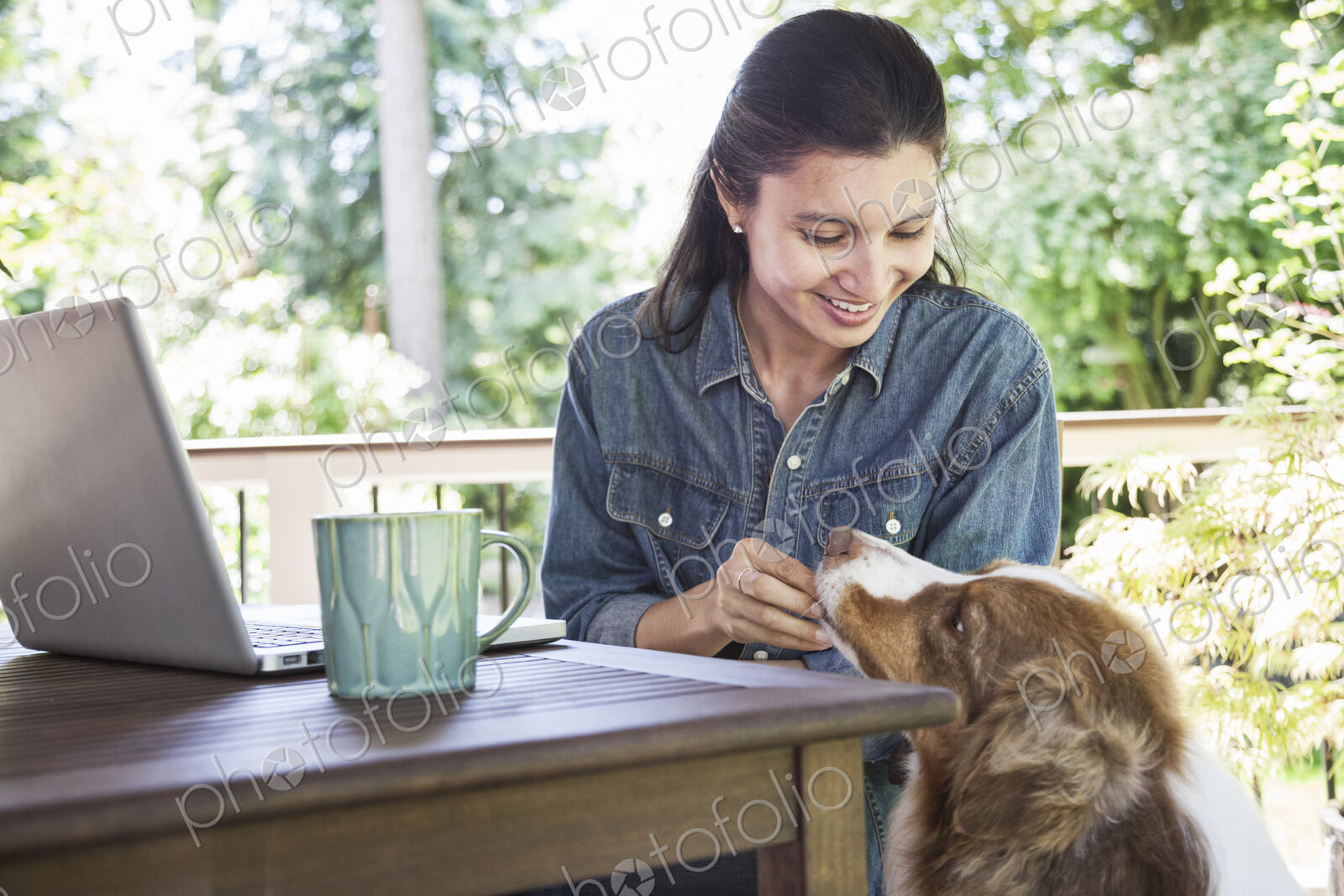 Mixed race caucasian woman working on her laptop at home with her dog.