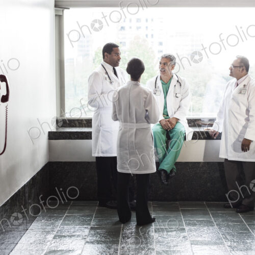 Mixed race doctors conferring in a hospital hallway.