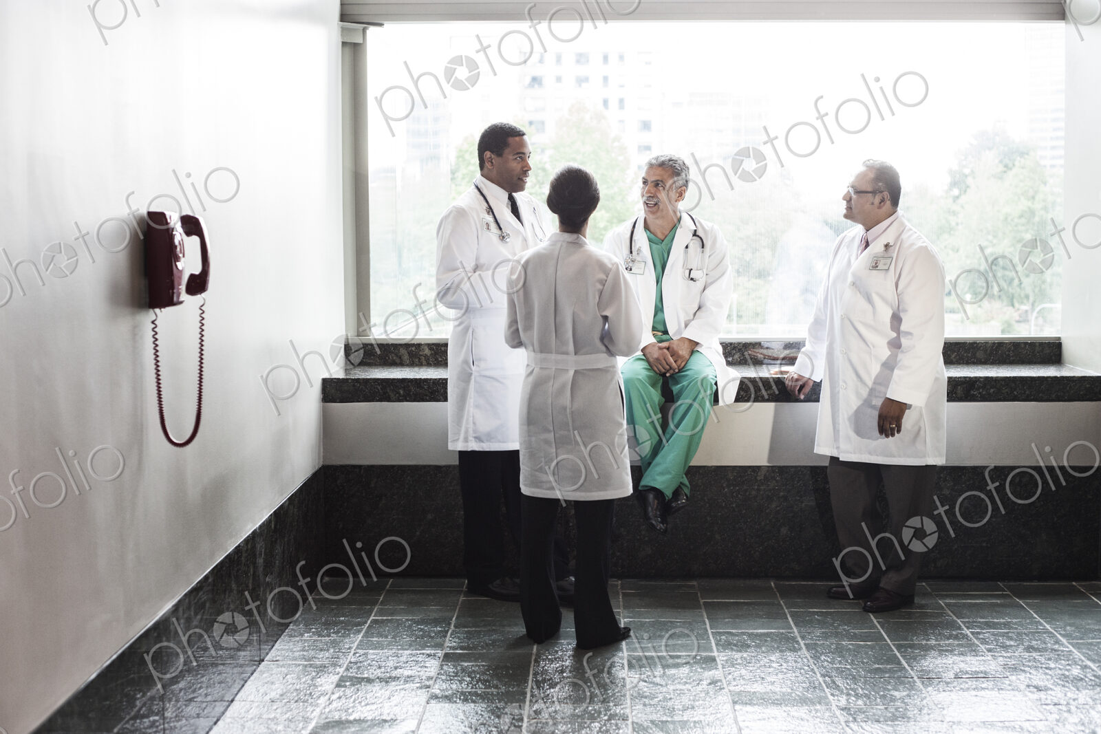 Mixed race doctors conferring in a hospital hallway.