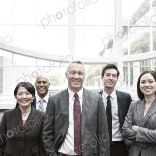 Mixed race group of business people standing in a glass covered walkway. Mixed race group of business people standing in a glass covered walkway.