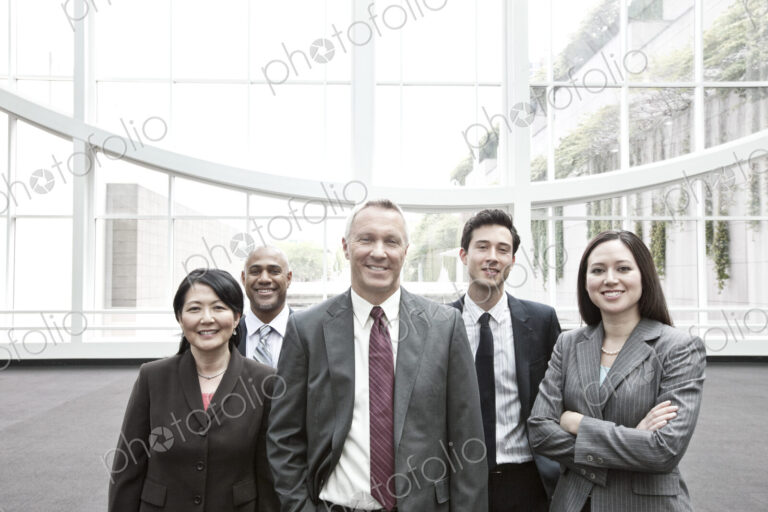 Mixed race group of business people standing in a glass covered walkway.
