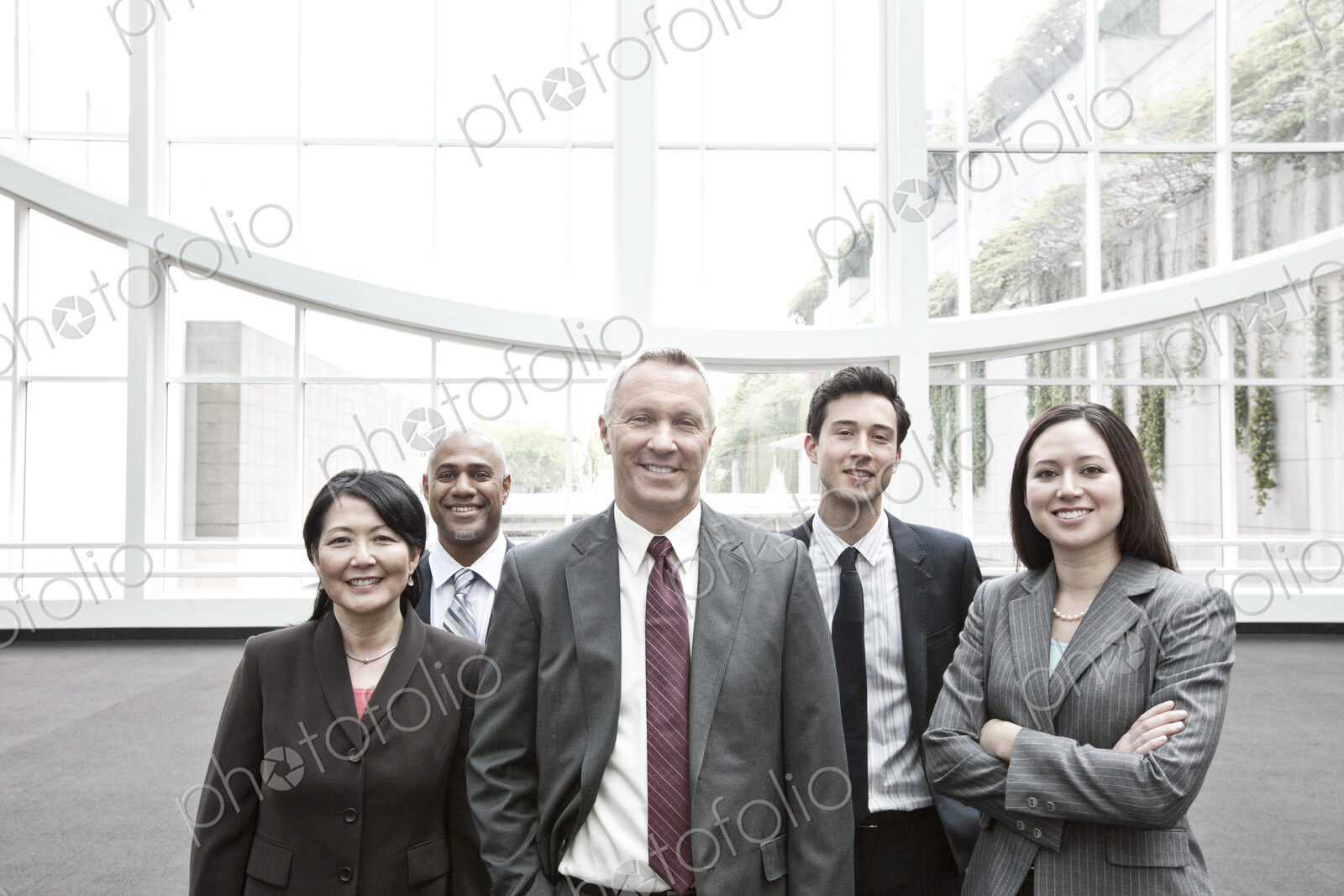 Mixed race group of business people standing in a glass covered walkway.