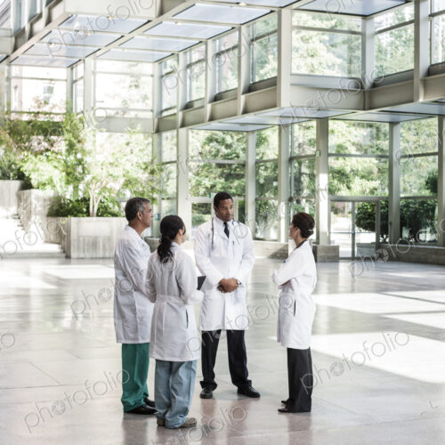 Mixed race group of doctors meeting in lobby of large hospital Mixed race group of doctors meeting in lobby of large hospital